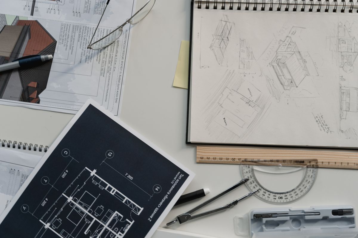 Schizzi e disegni tecnici di progettazione architettonica su un tavolo da lavoro